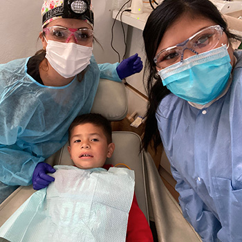 Patty and assistant posing with child in dentist chair